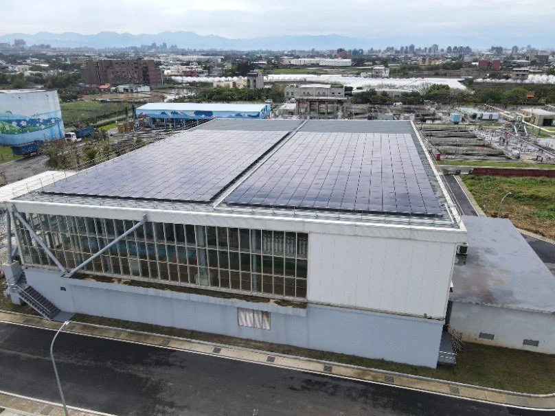Genuine rooftop PV photograph at the reclaimed water machinery room of the Taoyuan North District Water Resources Recycling Center, with restrained exposure and color adjustment.