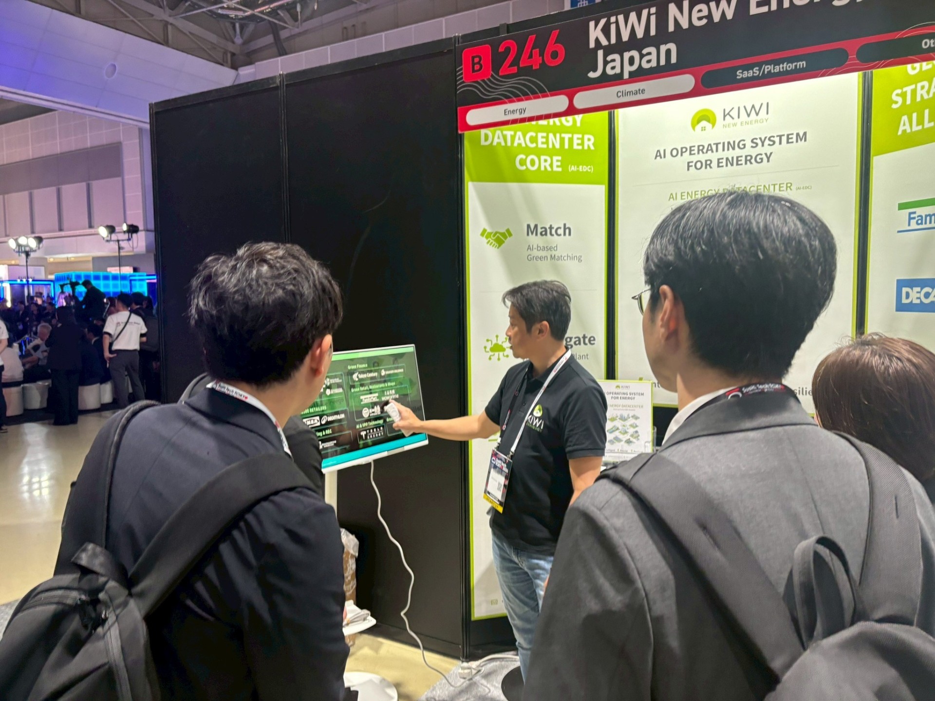 Live walkthroughs at the booth: Japanese visitors exploring how AI-EDC matches generation, storage, and per-site demand across hundreds of retail locations.